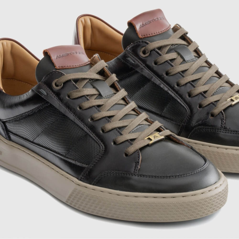 Pair of brown and Kaki sneakers with brown laces and soles on a light grey background