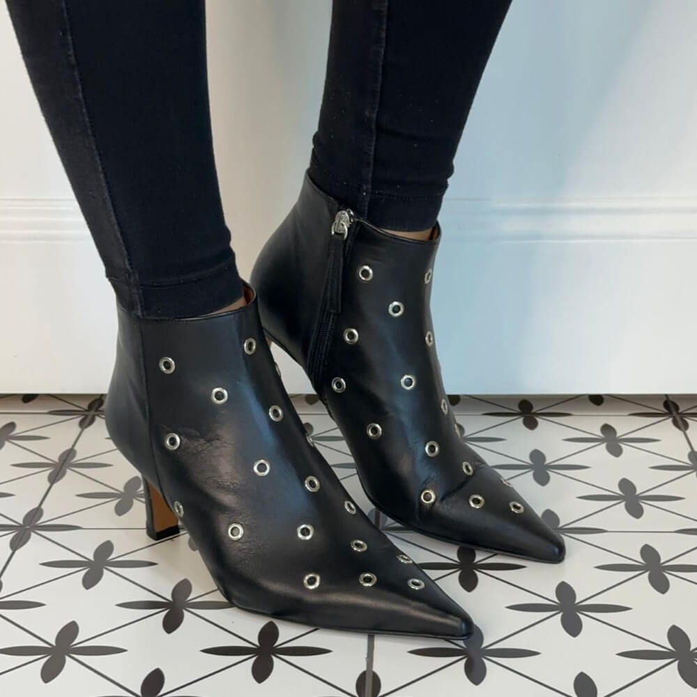 Black studded ankle boots worn with black jeans on a patterned floor. Ángel Alarcón Clarine 25558 Leather Ankle Boot-BLACK
