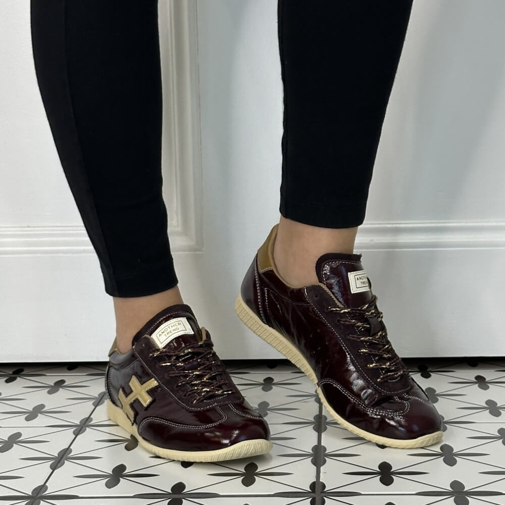 Another Trend Wine Patent Leather Trainers worn with black jeans on a tiled floor