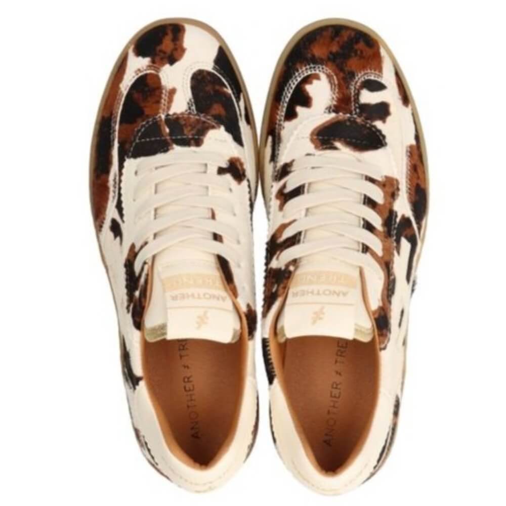 Pair of animal cow print sneakers on a white background
