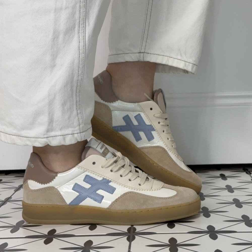 another trend Beige sneakers with blue geometric designs worn indoors on a patterned floor.
