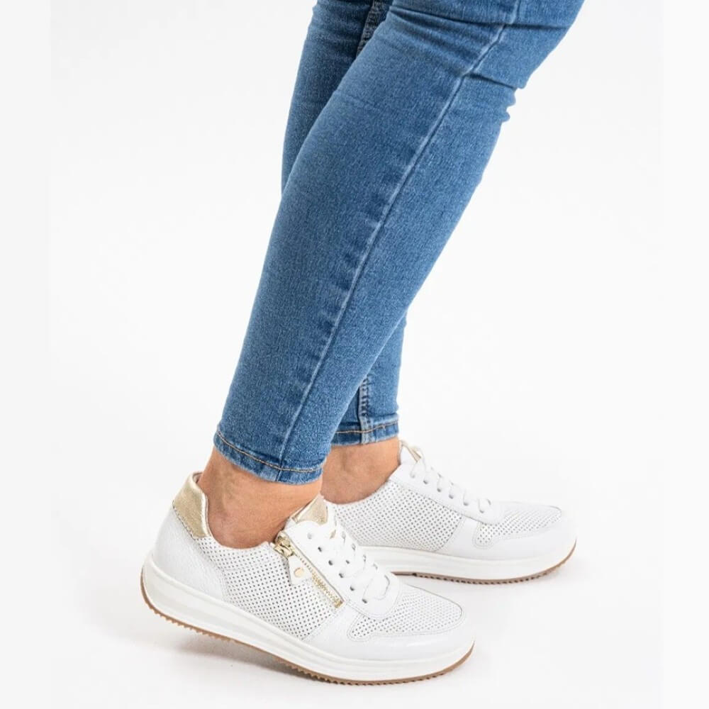 White sneakers worn with blue jeans on a white background White leather sneaker with gold zip and accents ara osaka