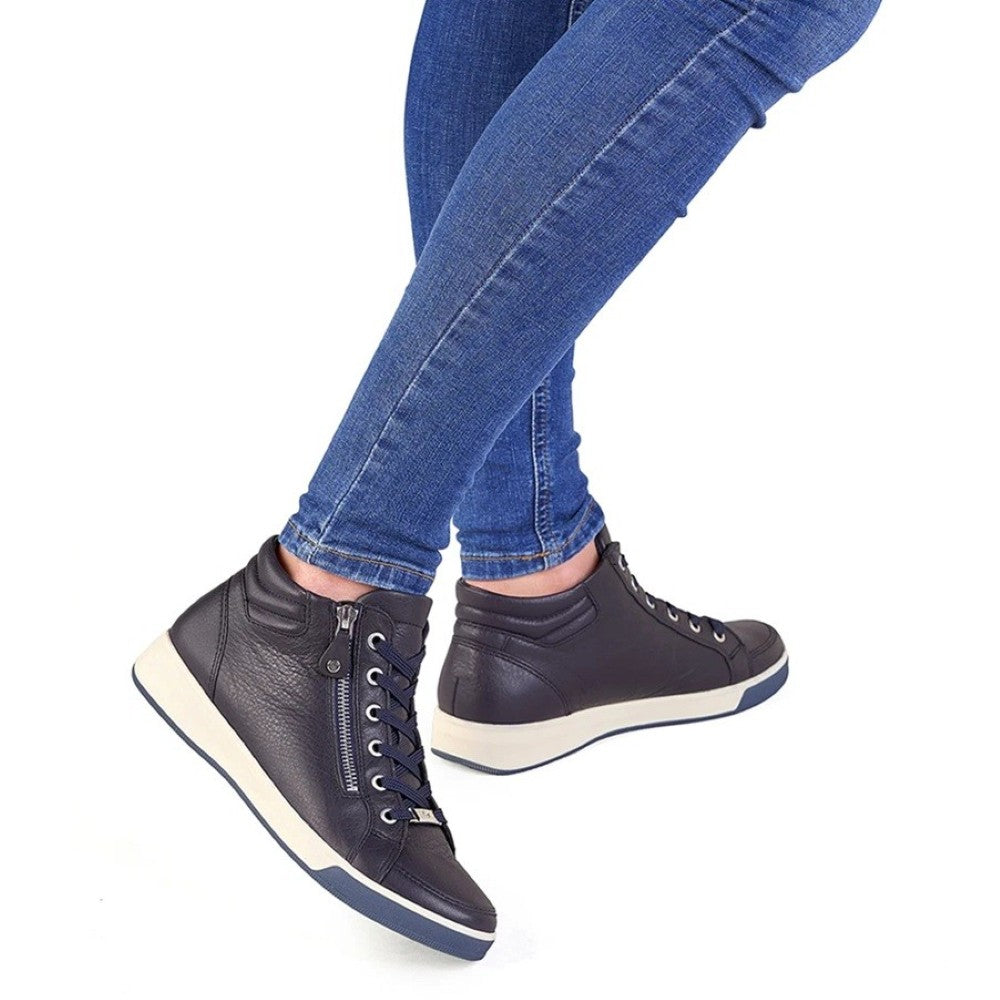 A person wearing blue skinny jeans and Ara Navy leather high-top sneakers with white soles, shown from the knees down against a plain white background.