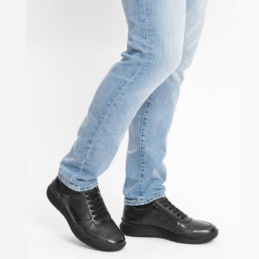 Black waterproof shoes worn with light blue jeans on a white background