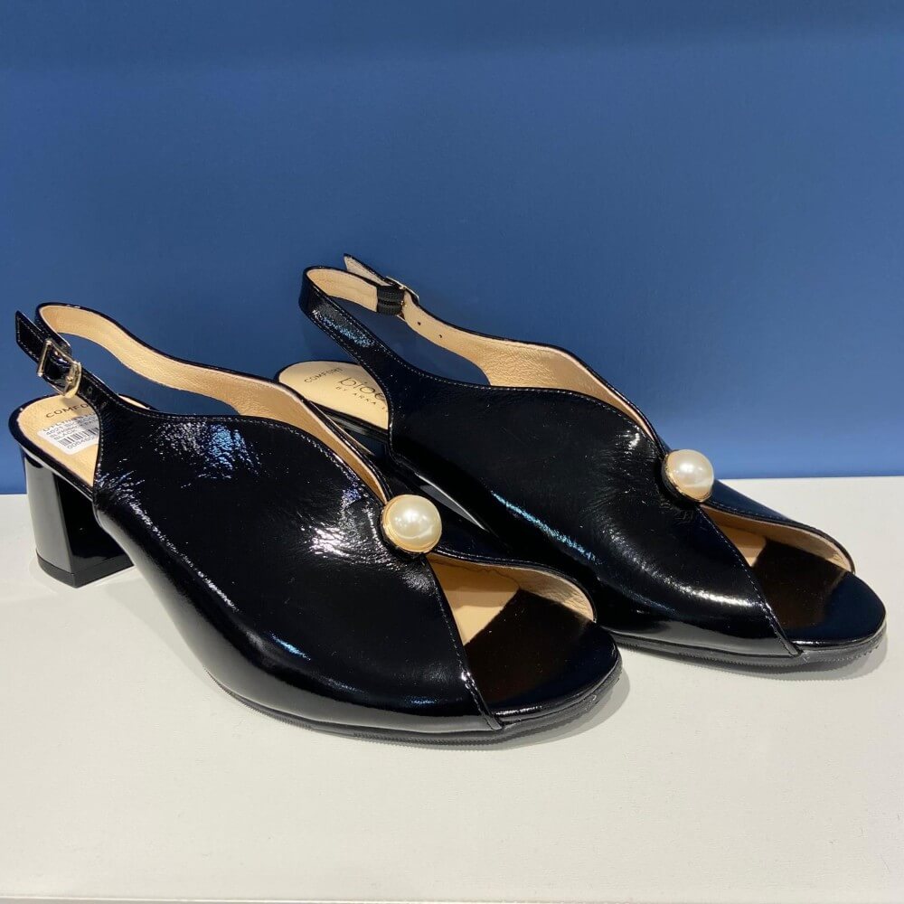 Bioeco Black sandal with a pearl accent on a white surface and blue background