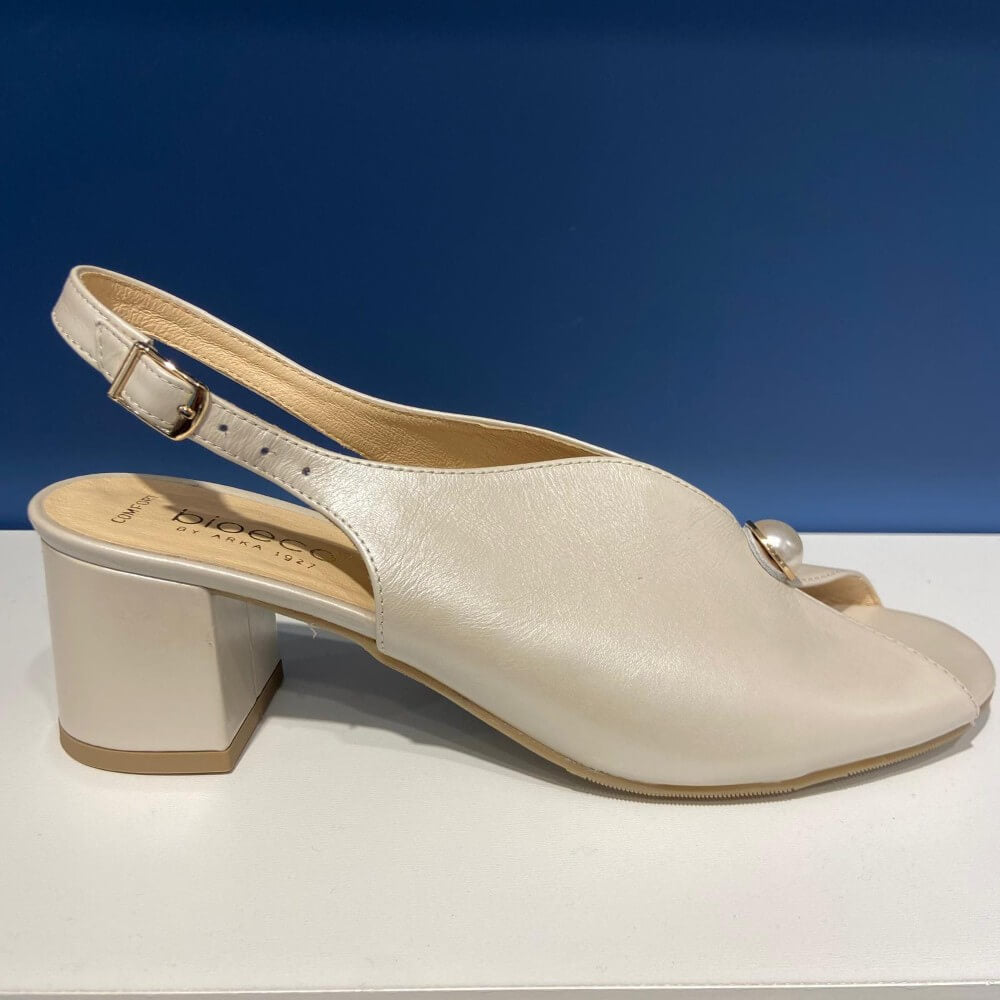 Bioeco Beige sandal with a block heel on a white surface with a blue background