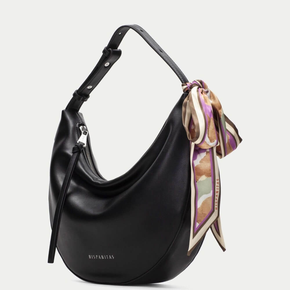 Black handbag with a colorful scarf draped over it on a light gray background