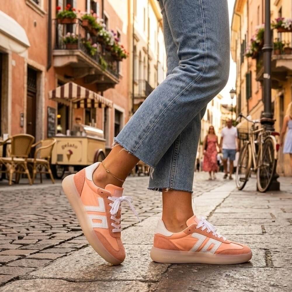 Person wearing Back 70 peach sneakers with white stripes on a cobblestone street in an urban setting.