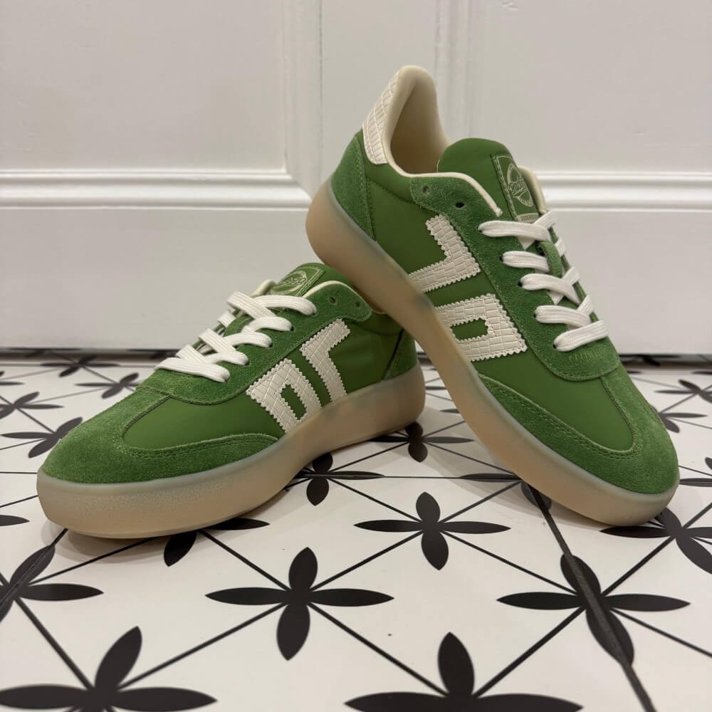 Back 70 Brooklyn Green sneakers with white laces on a black and white patterned floor.