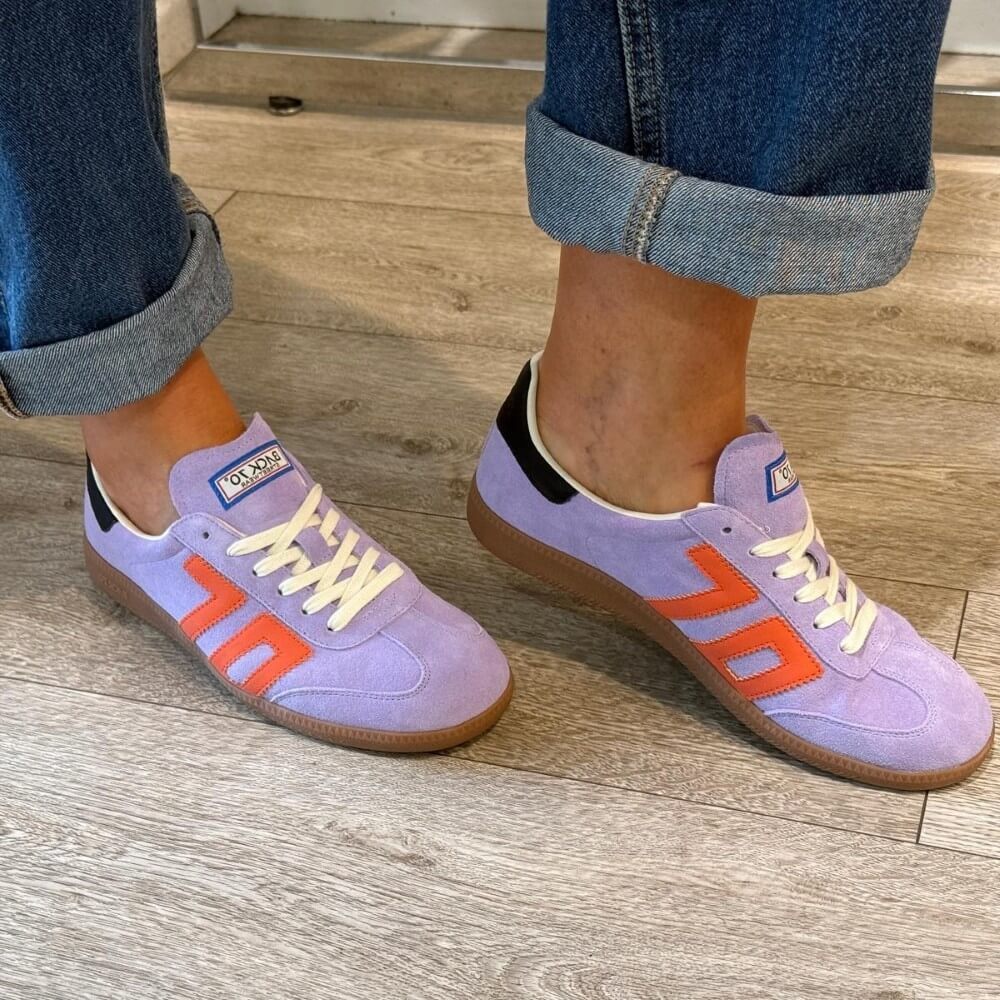 Back 70 Cloud Purple sneakers with orange accents worn on a wooden floor