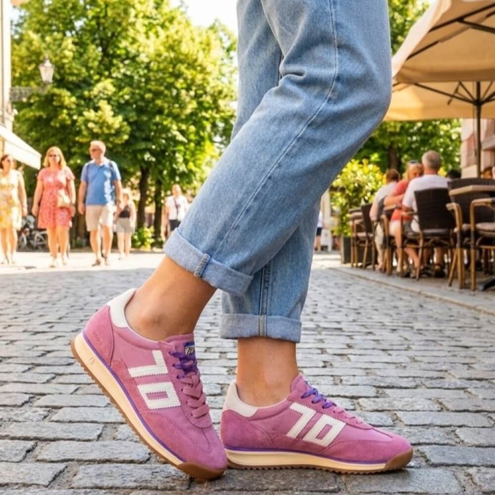 Person wearing pink Back 70 sneakers on a street with people and trees in the background