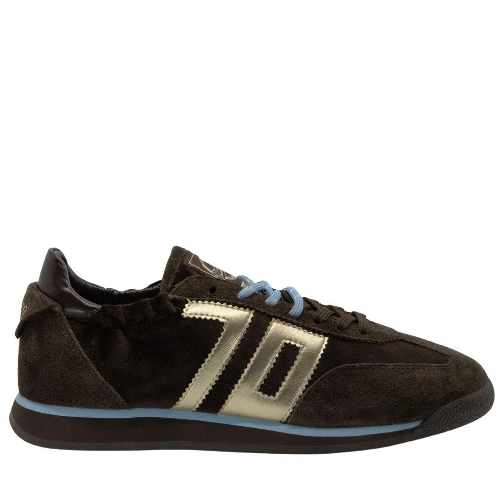 A Back 70 dark brown suede sneaker with metallic gold side stripes, light blue laces, and a light blue midsole accent, shown from a side profile on a white background.