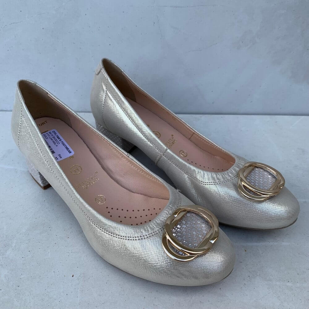 Pair of gold shoes with decorative buckles on a light gray background
