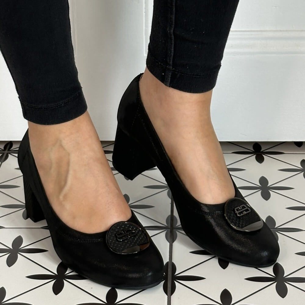 Black high-heeled shoes worn with black pants on a patterned floor. Bioeco 6844 Block Heel Black Shimmer Suede court shoes
