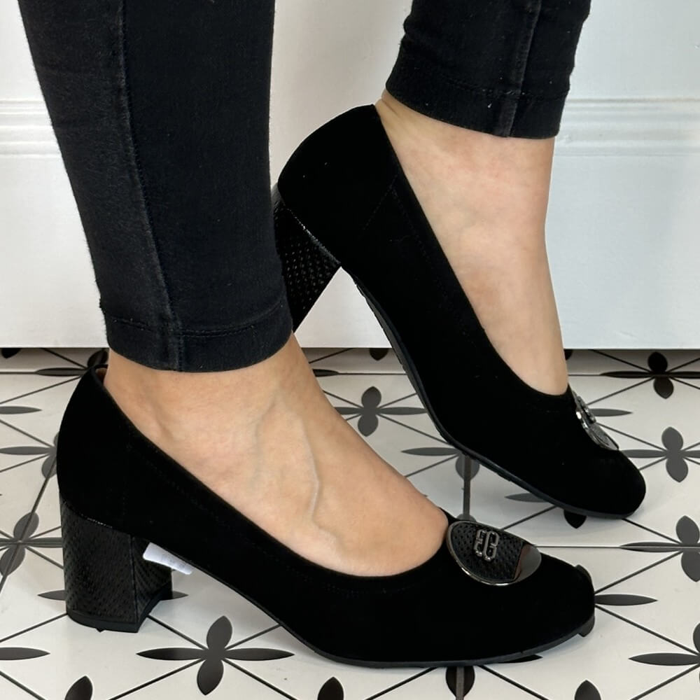 Black high-heeled shoes worn with black pants on a patterned floor. Bioeco 6844 Block Heel Black Suede court shoe