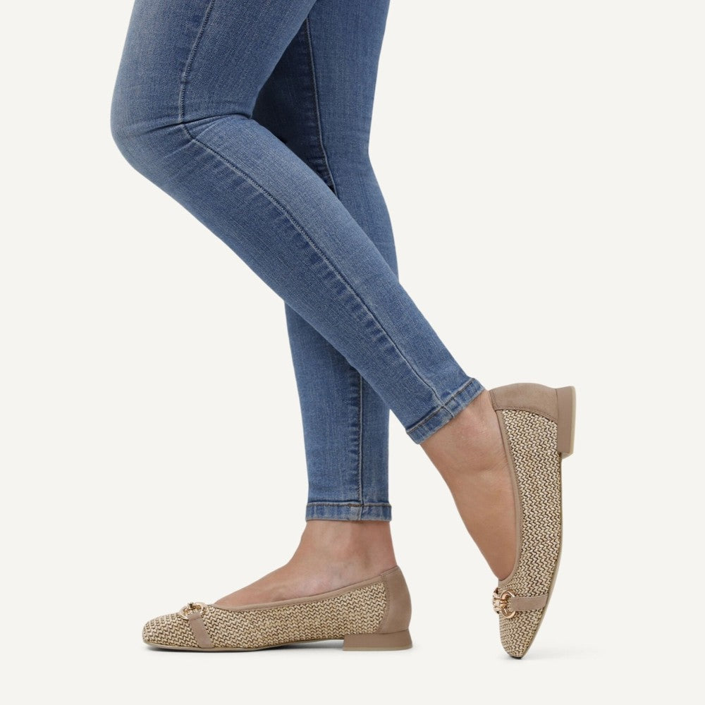Caprice Beige woven flats worn with blue jeans on a white background