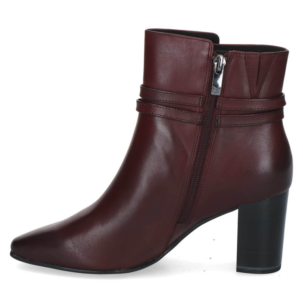 A Caprice dark brown leather ankle boot with a block heel, pointed toe, and a decorative strap with a gold-tone buckle detail around the ankle.