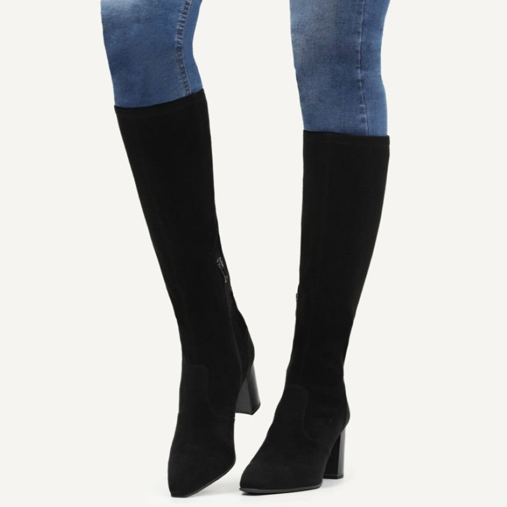Person wearing knee high black vegan boots with denim jeans