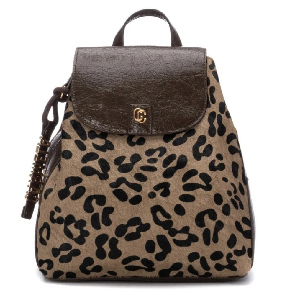 A Carmela leopard print backpack featuring a tan and black animal pattern with dark brown faux-leather trim, a top handle, and a small gold-tone logo clasp on the front flap.