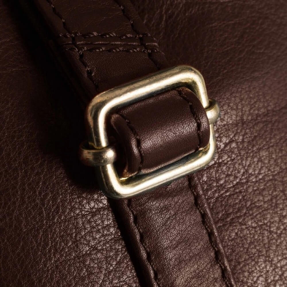 Close-up of a brown leather strap with a gold buckle