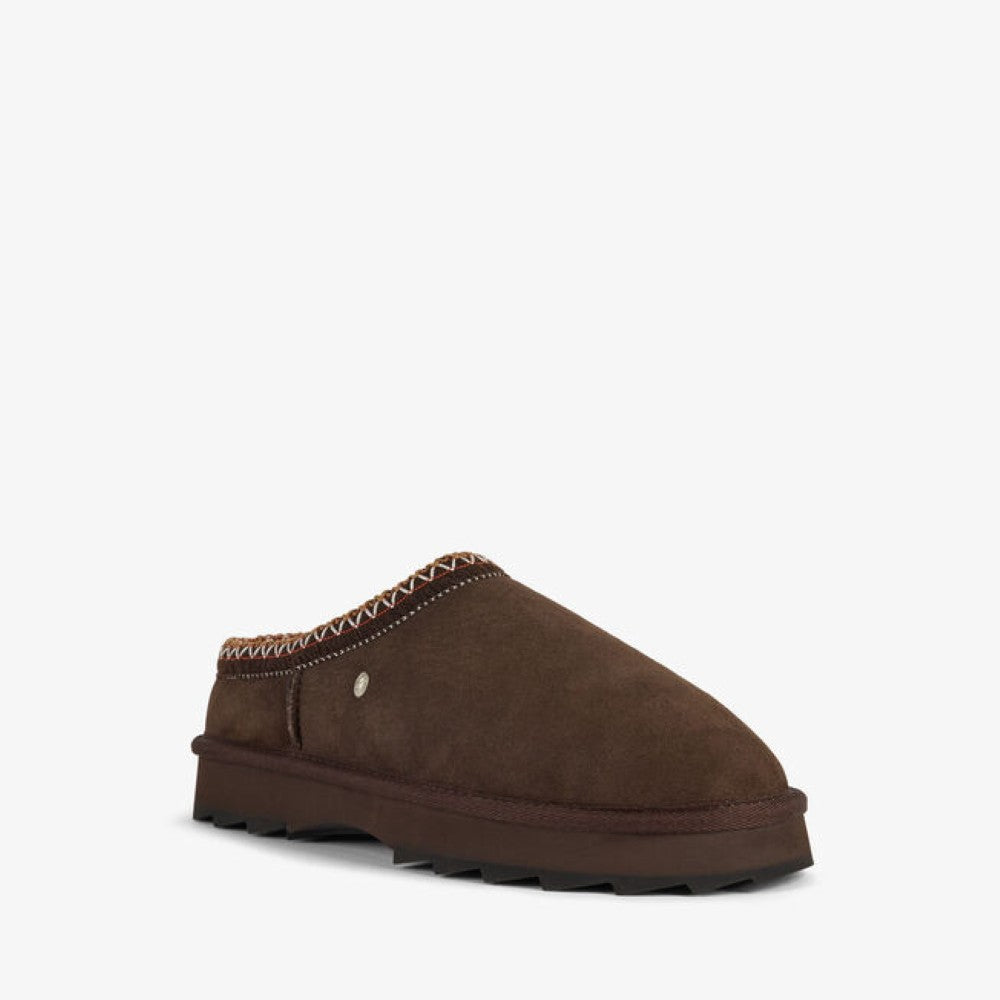 A single dark brown suede slip-on clog shoe with a thick dark brown sole, decorative zigzag stitching around the collar, and a small silver metal rivet, shown against a plain white background.