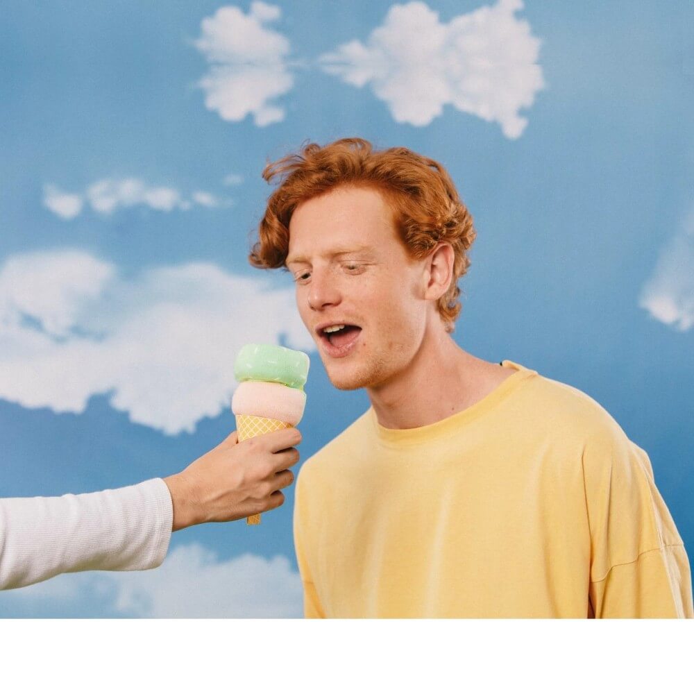 man eating a Pair of green and cream socks packaged like an ice-cream