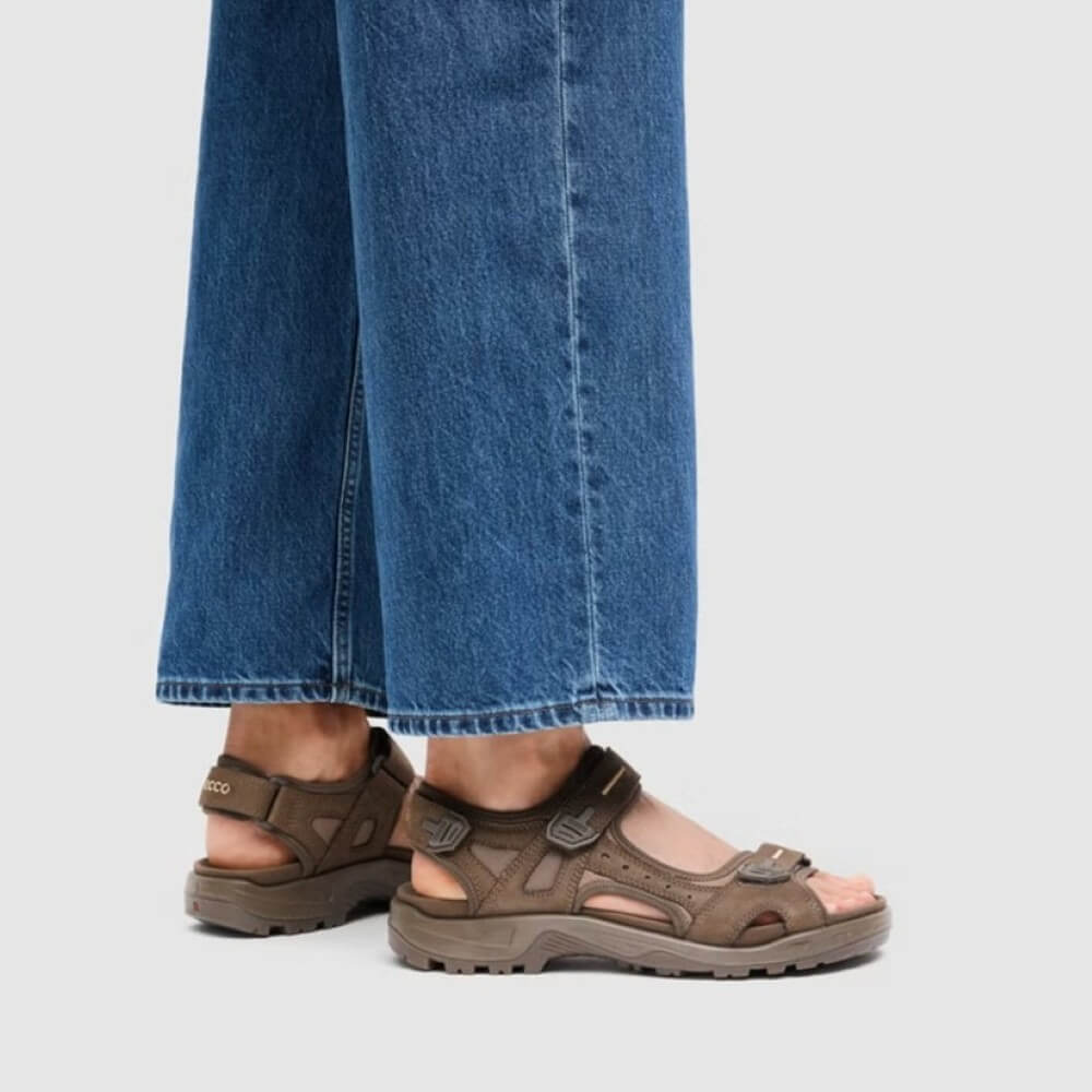Person wearing Ecco offroad Brown sandal with multiple straps on a white background