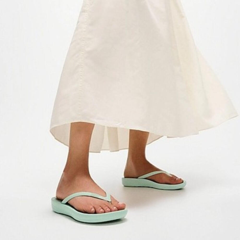 Person wearing light green sandals on a white background