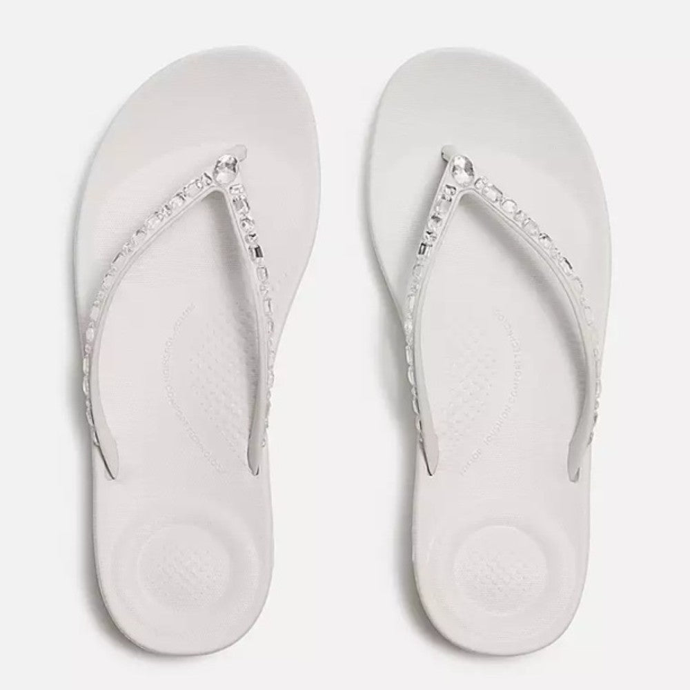 Pair of white flip-flops with decorative straps on a light gray background