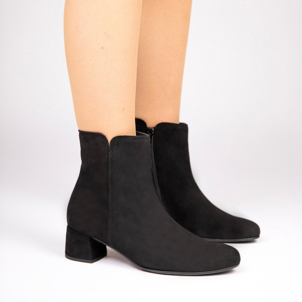 Gabor Black suede ankle boots with a low block heel, shown on a model's feet against a light grey background.