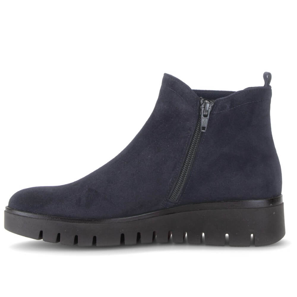 A Gabor navy blue suede ankle boot with a side zip and a chunky black lug sole, shown from a side profile view on a white