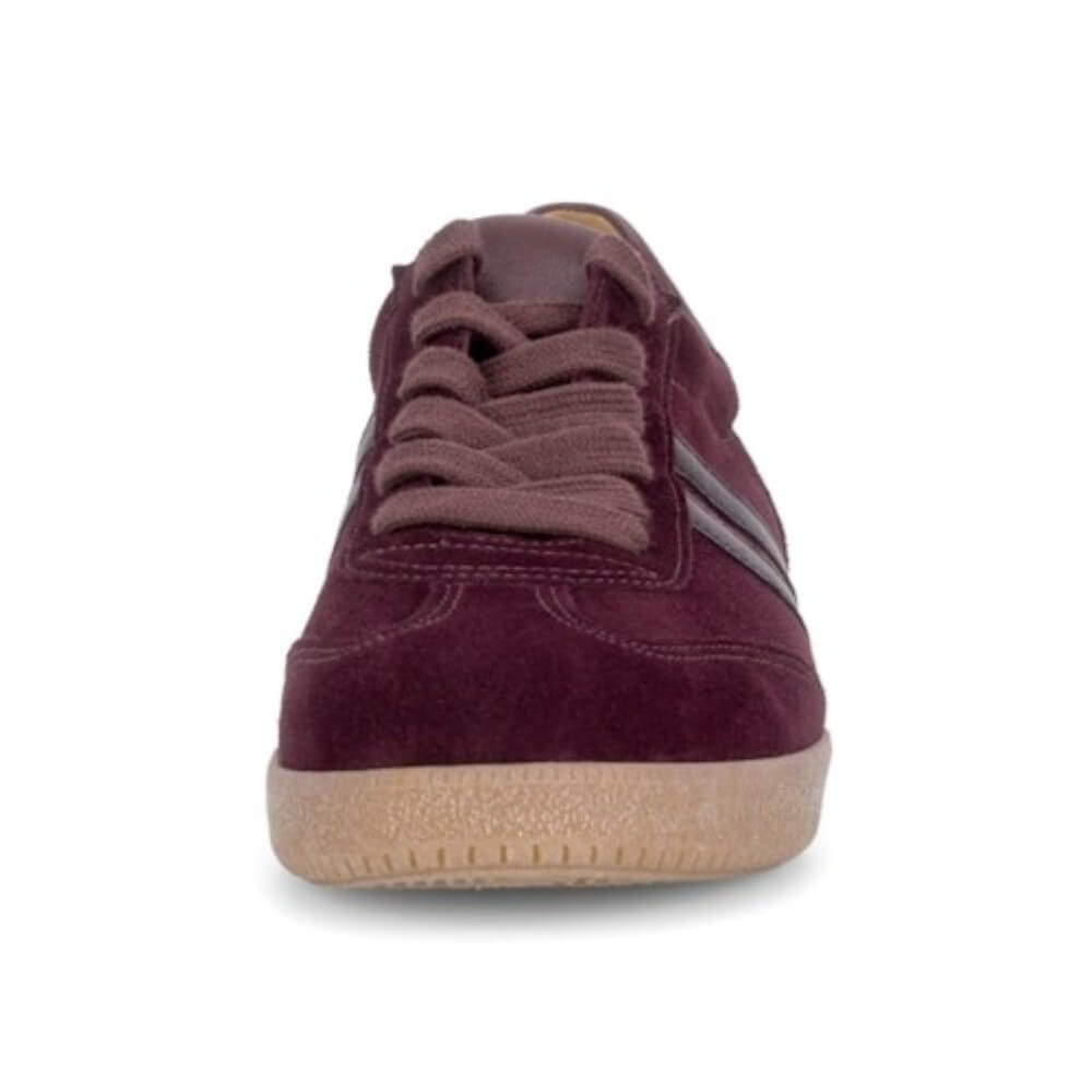 A single low-top suede sneaker in a deep burgundy color, featuring matching burgundy laces and a light tan rubber sole, shown from a front-facing perspective on a white background.