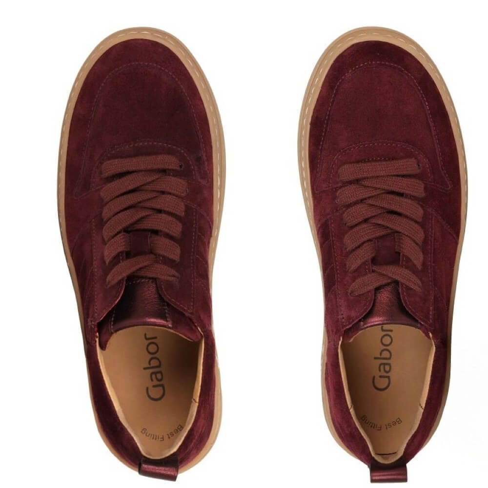 Pair of maroon suede shoes with brown soles on a white background
