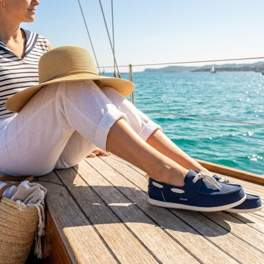 Person wearing heydude navy boat shoes by the sea
