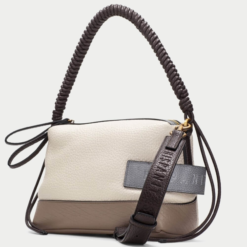 A colour-blocked handbag with a textured off-white top half, a taupe-brown bottom half, and a dark brown coiled shoulder strap. A dark grey leather patch on the front features the brand name 'HISPANITAS' in gold lettering.
