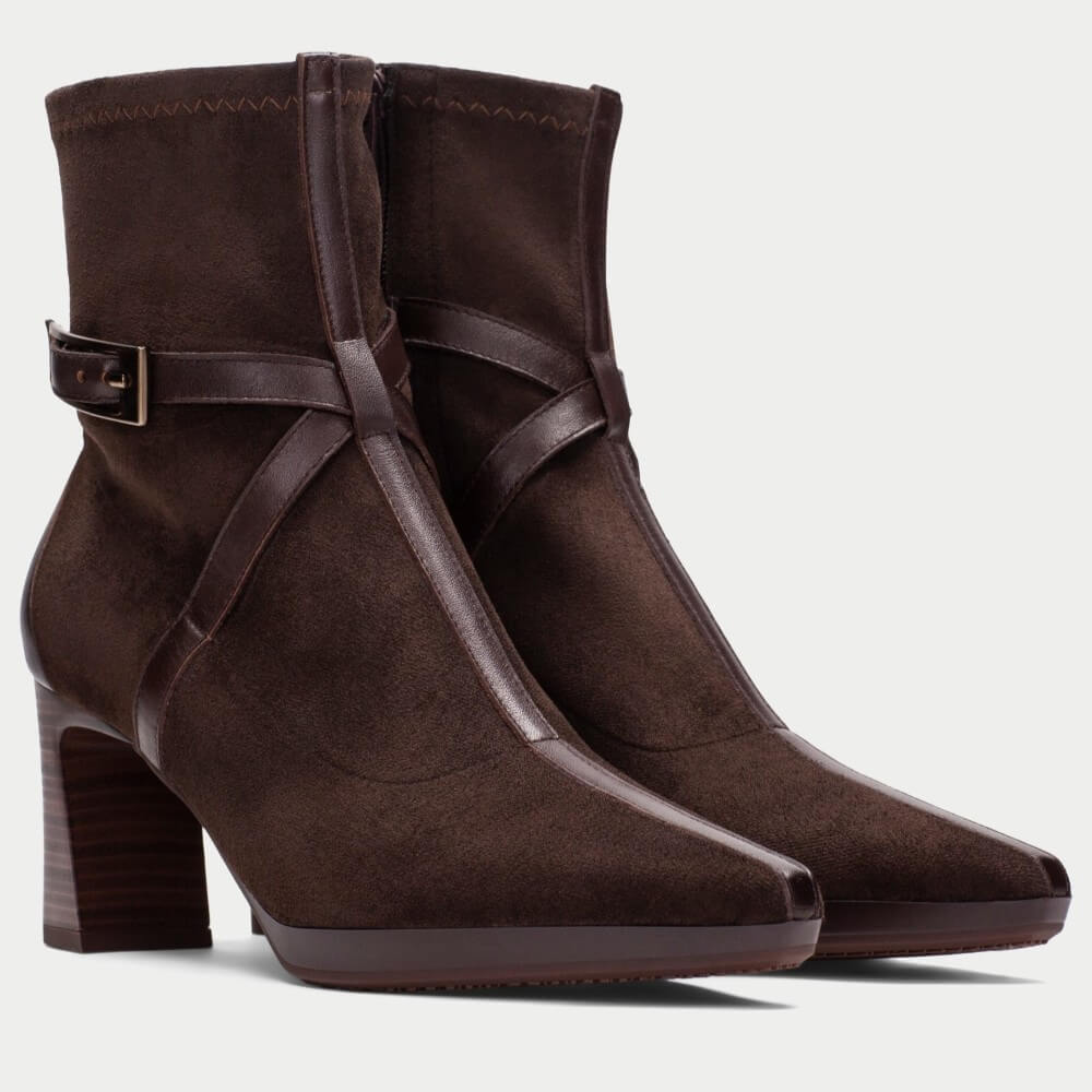 A pair of Hispanitas dark brown suede ankle boots with a pointed toe, a stacked block heel, and a decorative brown leather strap with a gold-tone buckle around the ankle.