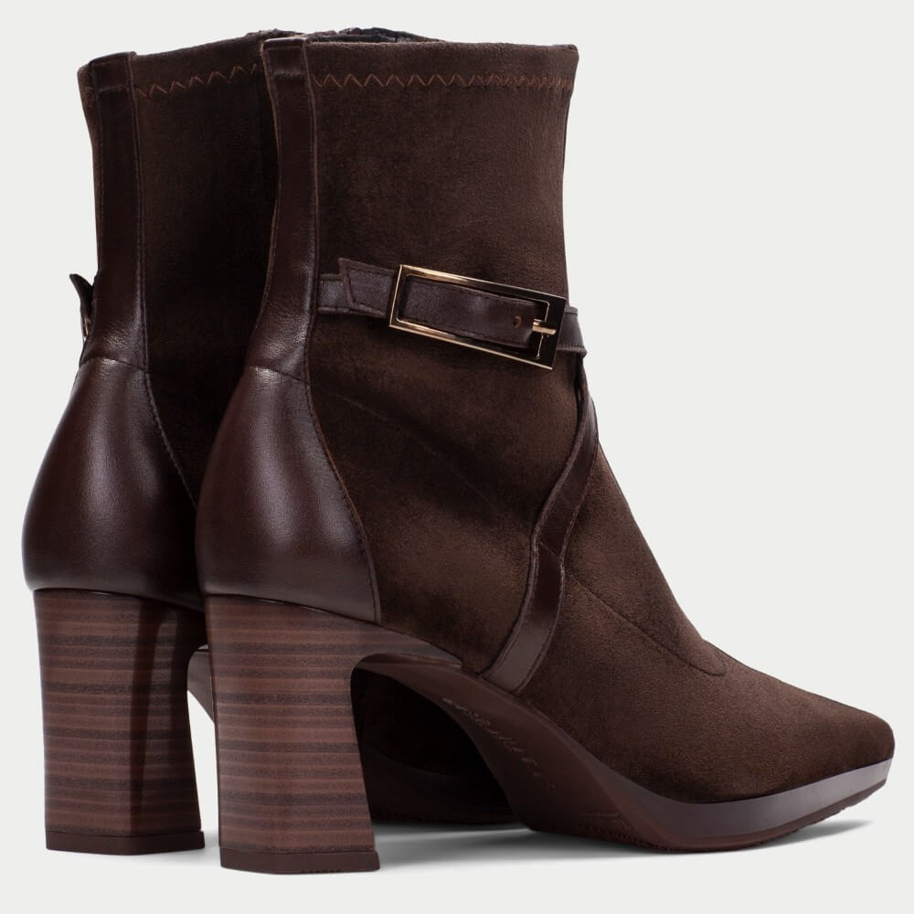 A pair of Hispanitas dark brown suede ankle boots with a pointed toe, a stacked block heel, and a decorative brown leather strap with a gold-tone buckle around the ankle.