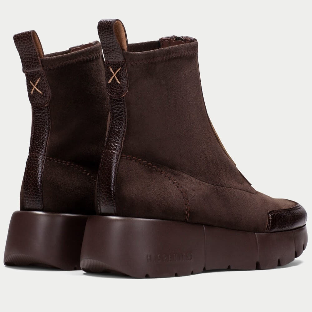 A pair of Hispanitas dark brown ankle boots featuring a mix of suede and textured leather panels, a chunky lug sole, and pull tabs with an 'X' detail, shown against a light grey background.