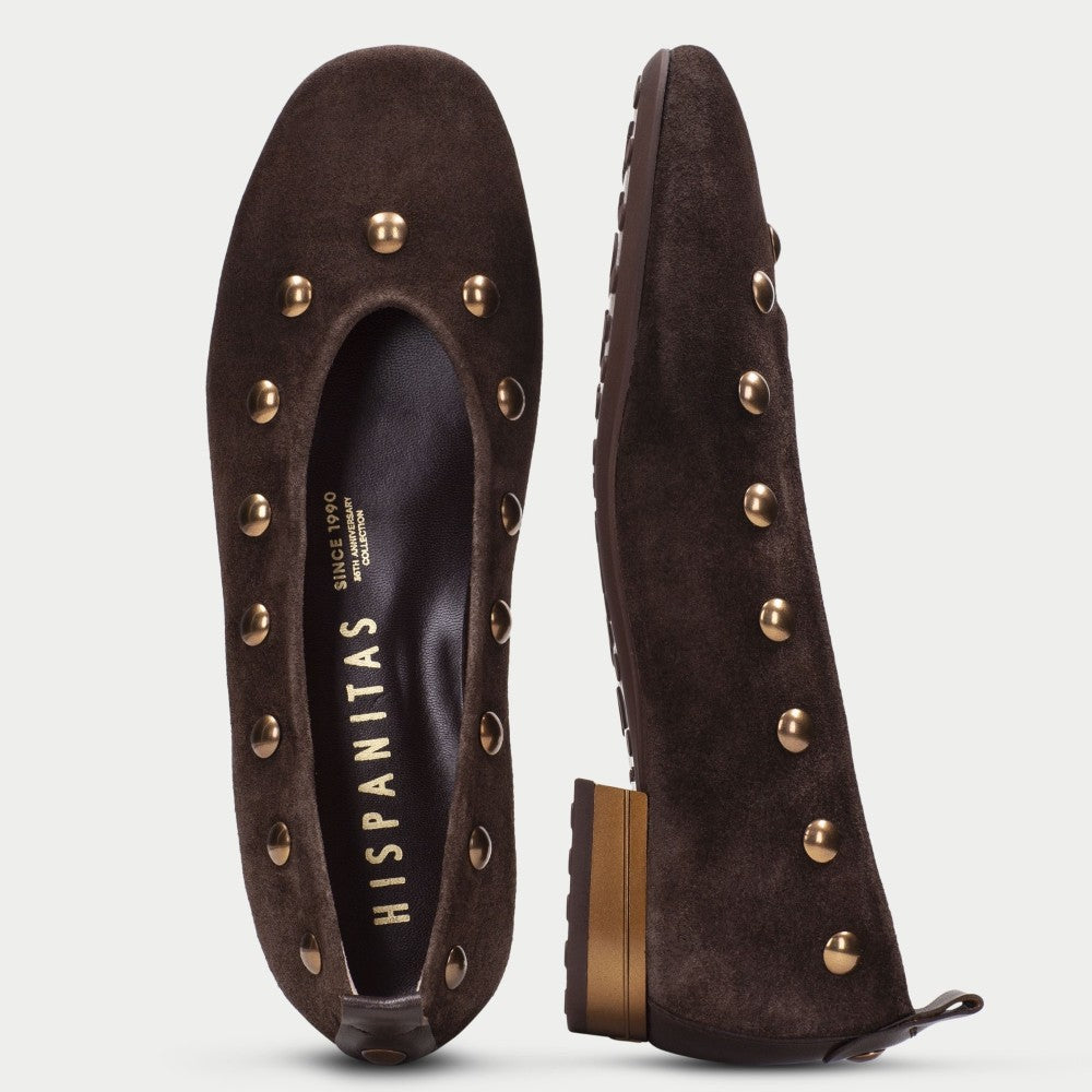 A pair of dark brown suede flat shoes decorated with gold-tone metal studs, shown from both the top and side views on a light gray background. The insole displays the brand name 'HISPANITAS'.