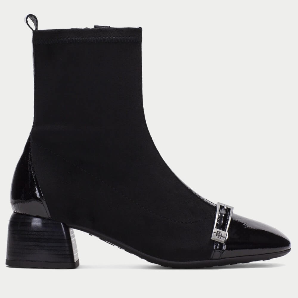 A Hispanitas black ankle boot with a patent leather pointed toe and a silver buckle detail, shown in a side profile on a light gray background.