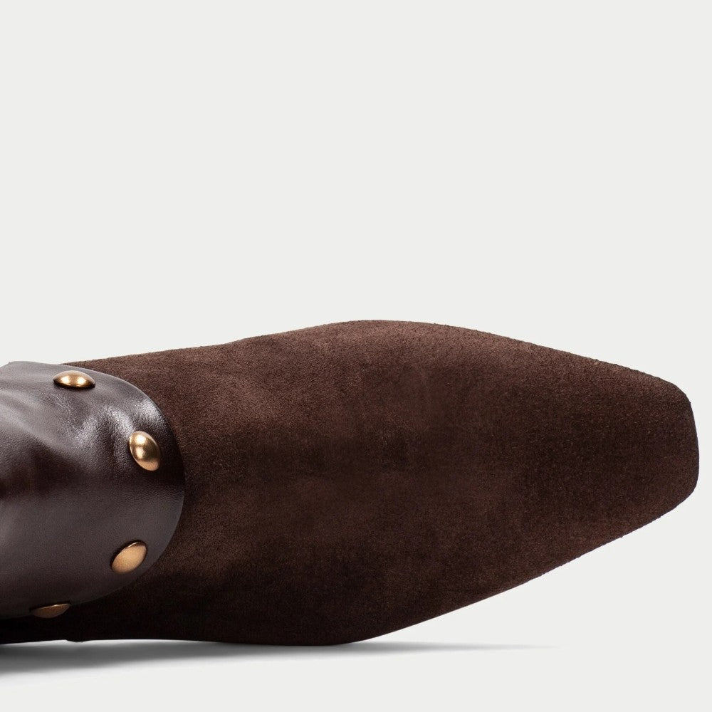 A Hispanitas dark brown suede and leather ankle boots with a pointed toe and a wide leather cuff embellished with gold-tone studs, shown against a light grey background.