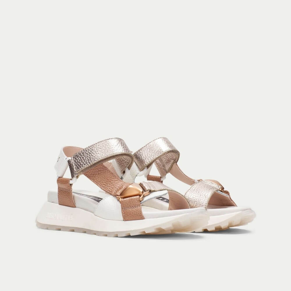 Pair of rose gold and tan sandals on a light gray background