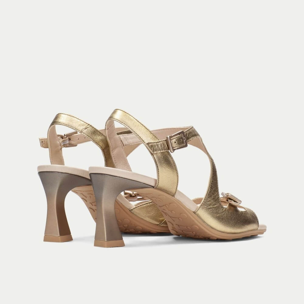 Gold high-heeled shoes on a light gray background