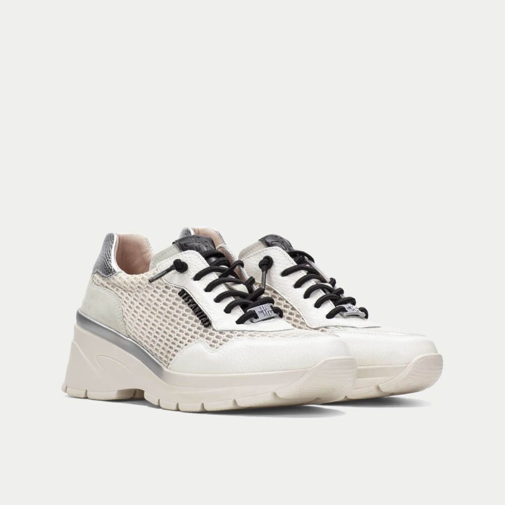White sneakers with black laces on a light gray background