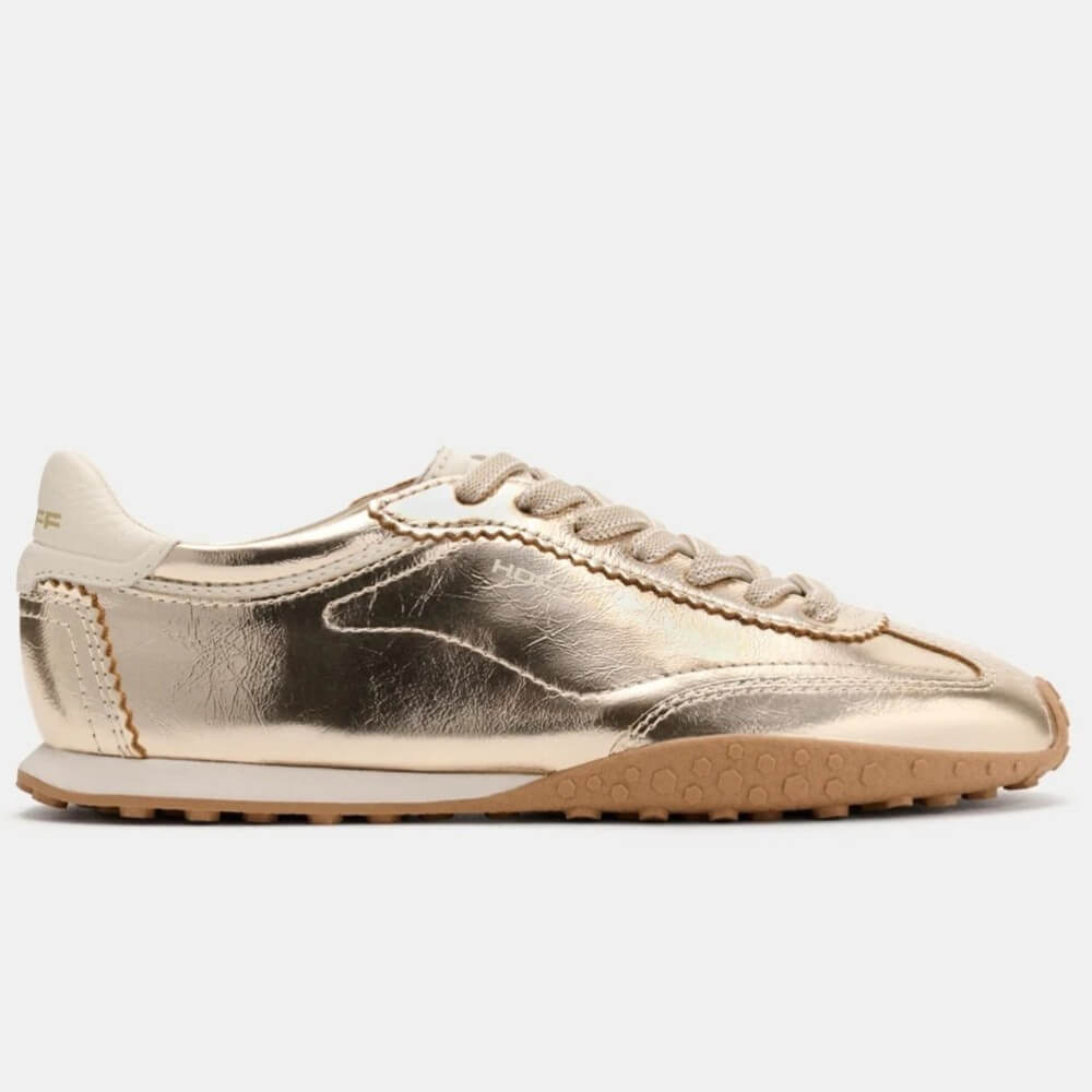 A Hoff metallic gold leather sneaker with beige laces, a cream collar, and a brown gum sole, shown in a side profile on a light grey background.