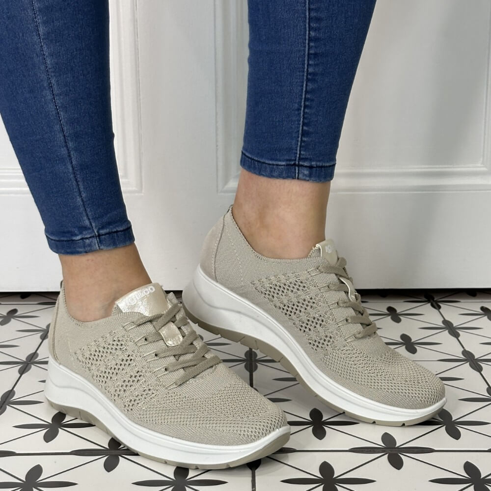 Person wearing beige sneakers with white soles on a tiled floor.
