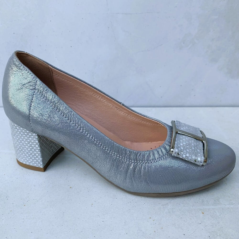 A silver court shoe with a block heel and a soft grey/silver upper. It features a matching bow and block heel, and a pink insole.