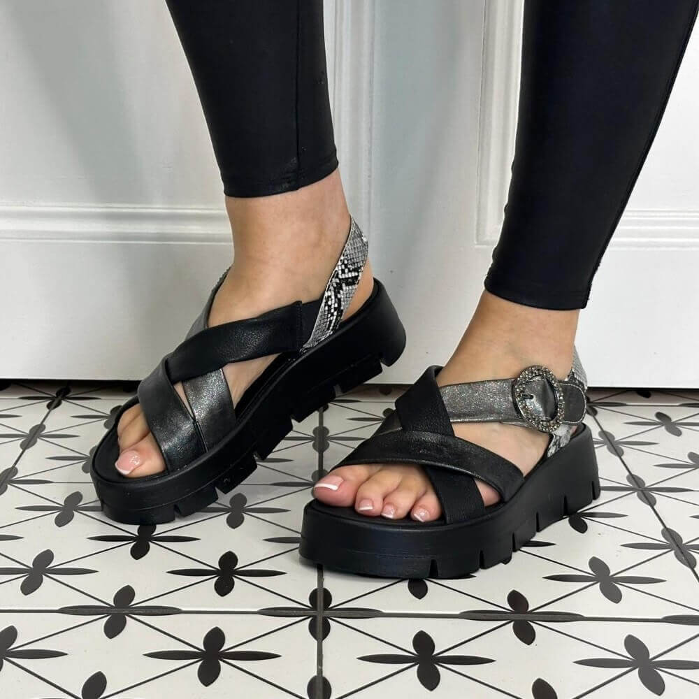 Igi & Co Black platform sandals with silver embellishments worn by a person on a patterned floor.