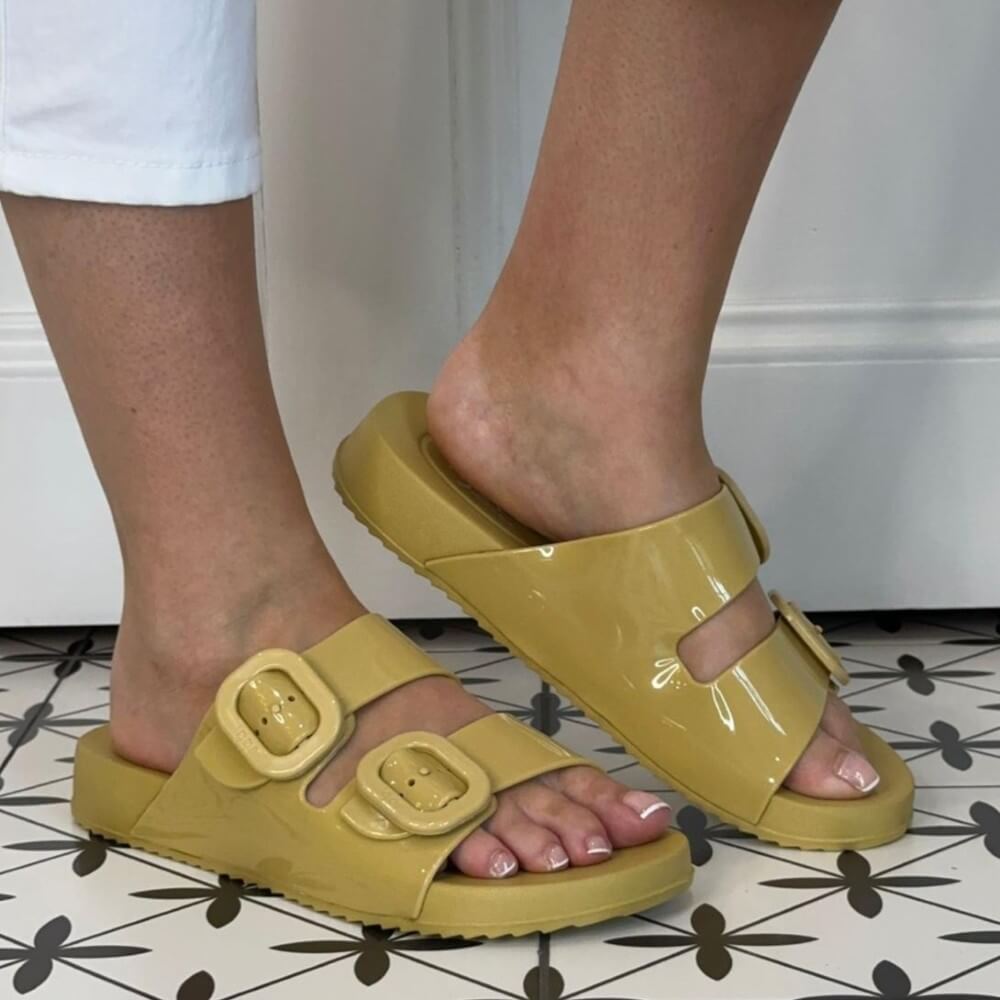 Igor Yellow slides with buckles worn by a person on a patterned floor.