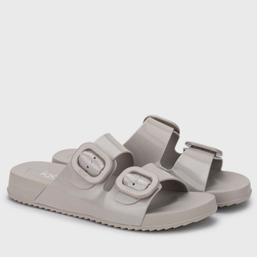Pair of beige sandals with buckles on a light gray background